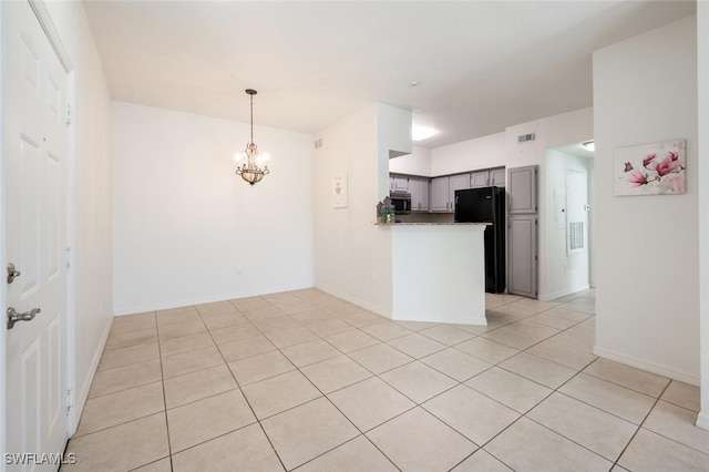 kitchen with an inviting chandelier, kitchen peninsula, gray cabinets, black refrigerator, and light tile patterned floors