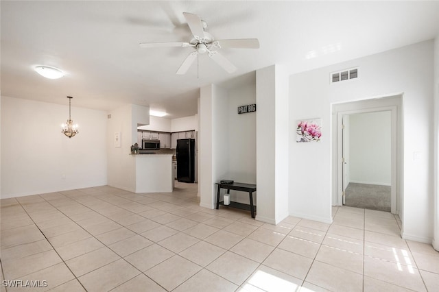 unfurnished living room with ceiling fan with notable chandelier and light tile patterned floors