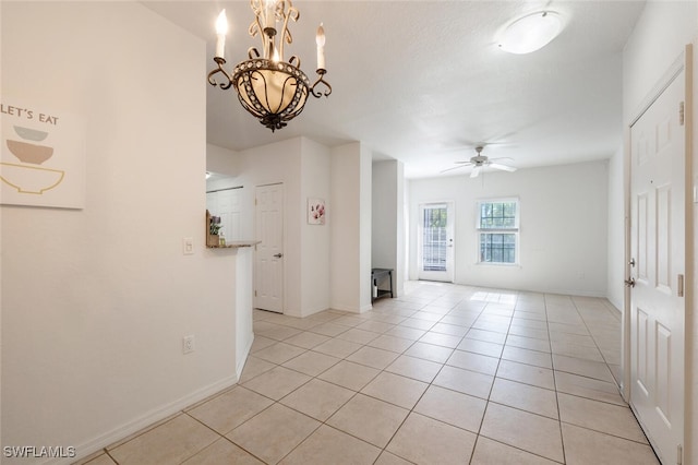 unfurnished room with light tile patterned floors and ceiling fan with notable chandelier