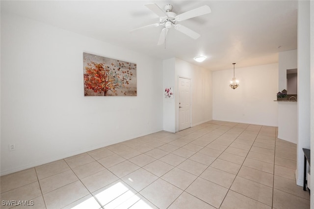 empty room with light tile patterned floors and ceiling fan with notable chandelier