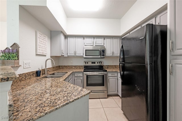 kitchen with gray cabinetry, sink, dark stone counters, light tile patterned flooring, and appliances with stainless steel finishes