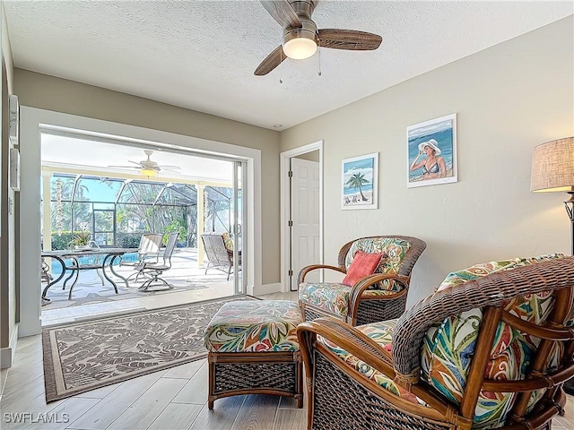 sitting room featuring a swimming pool, light hardwood / wood-style floors, and a textured ceiling