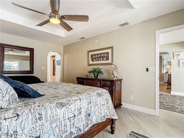 bedroom featuring a tray ceiling, light hardwood / wood-style flooring, and ceiling fan