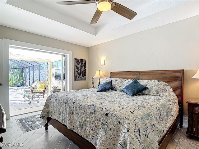 bedroom featuring access to exterior, hardwood / wood-style floors, a tray ceiling, and ceiling fan