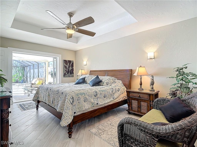 bedroom featuring access to outside, a tray ceiling, and ceiling fan