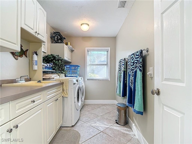 laundry area with cabinets, independent washer and dryer, light tile patterned floors, and sink