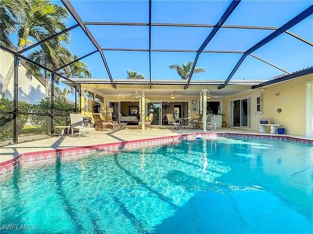 view of swimming pool with ceiling fan, a lanai, and a patio