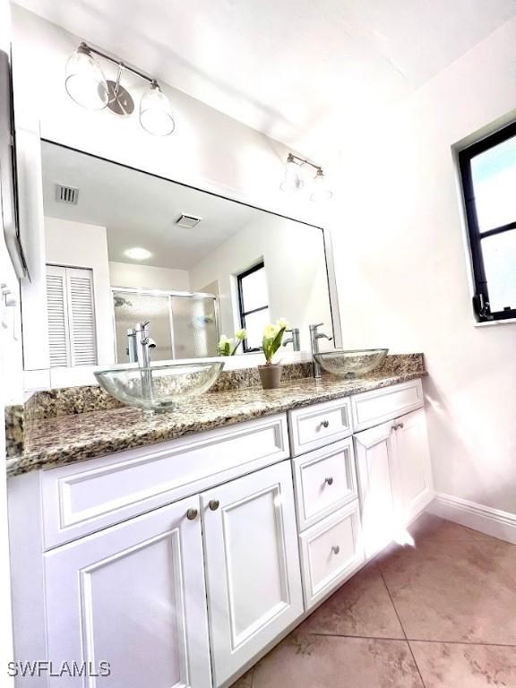 bathroom with tile patterned floors, a shower with door, and vanity