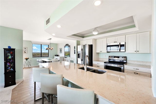 kitchen with white cabinets, appliances with stainless steel finishes, decorative light fixtures, and sink