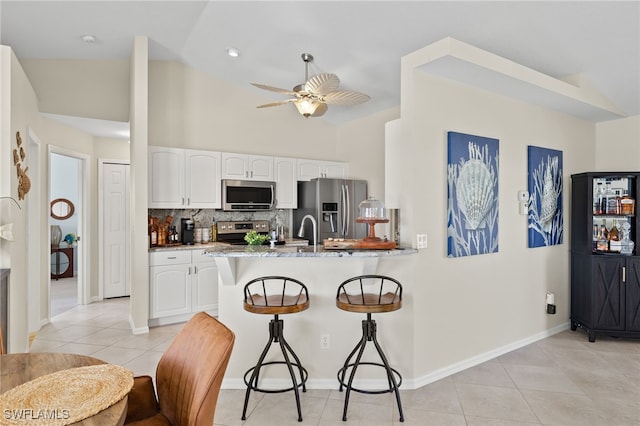 kitchen featuring kitchen peninsula, white cabinets, stainless steel appliances, and lofted ceiling