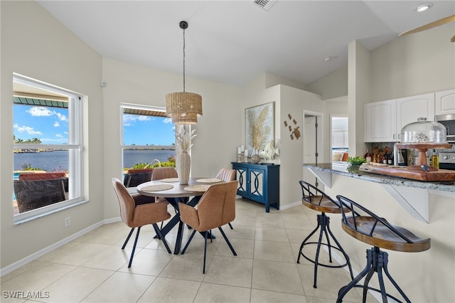 tiled dining space featuring a water view and vaulted ceiling