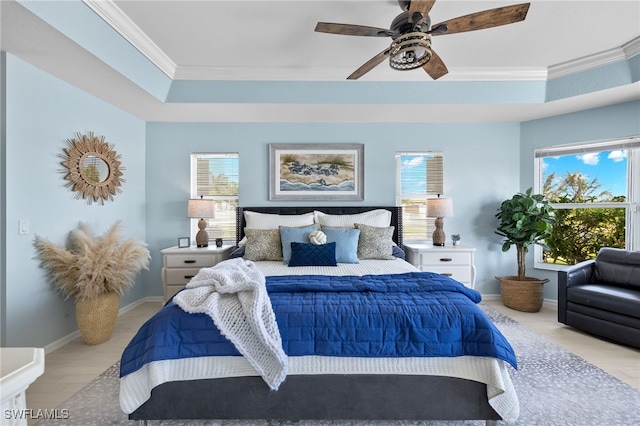 bedroom featuring multiple windows, a raised ceiling, and ceiling fan