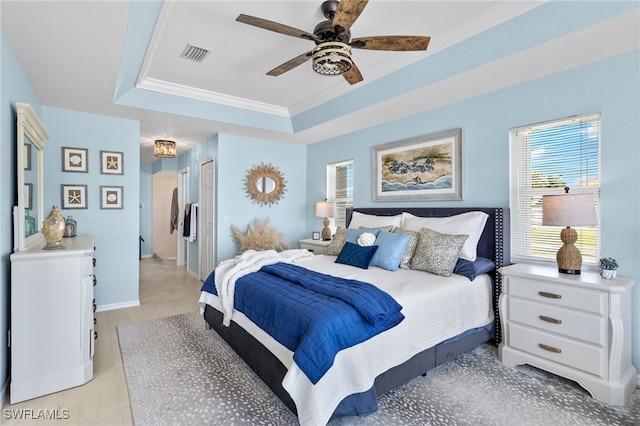 bedroom with ceiling fan, a raised ceiling, light hardwood / wood-style flooring, crown molding, and a closet