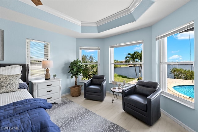 bedroom featuring a water view, a raised ceiling, multiple windows, and ornamental molding