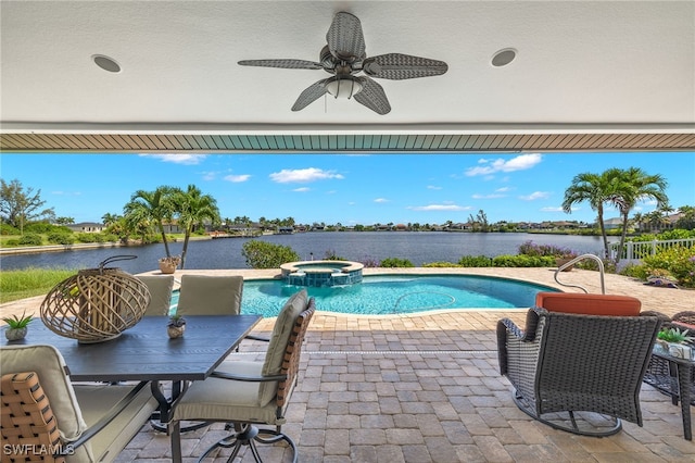 view of pool featuring an in ground hot tub, a water view, ceiling fan, and a patio area