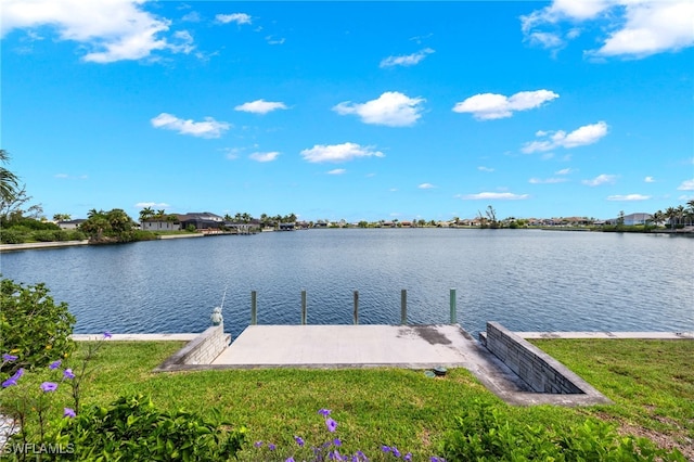 view of dock with a lawn and a water view