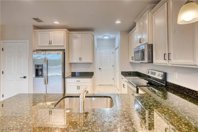 kitchen featuring dark stone counters, white cabinets, and stainless steel appliances