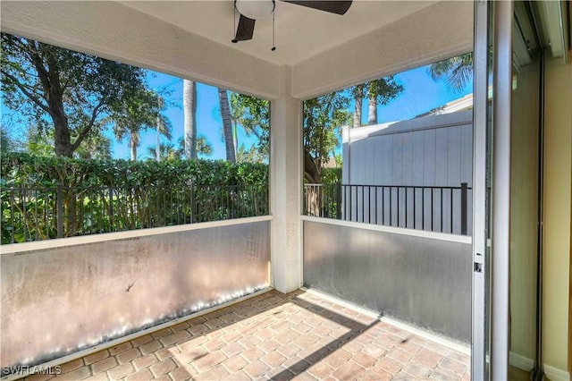 unfurnished sunroom featuring ceiling fan