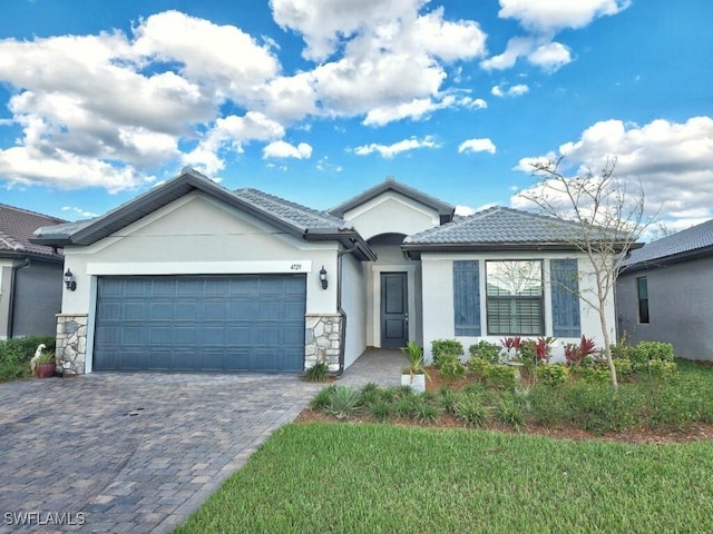 view of front facade with stone siding, a tiled roof, an attached garage, decorative driveway, and stucco siding