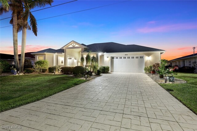 ranch-style house with a garage and a yard