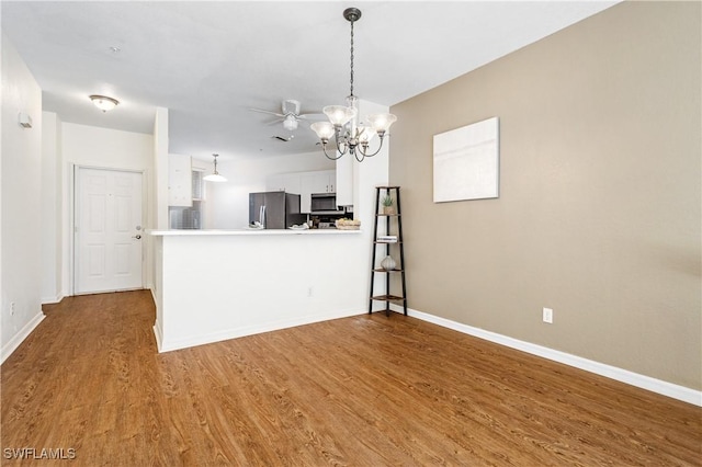 kitchen featuring stainless steel appliances, kitchen peninsula, wood-type flooring, and white cabinets