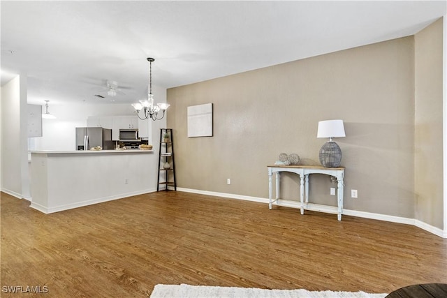 unfurnished living room with hardwood / wood-style floors and ceiling fan with notable chandelier