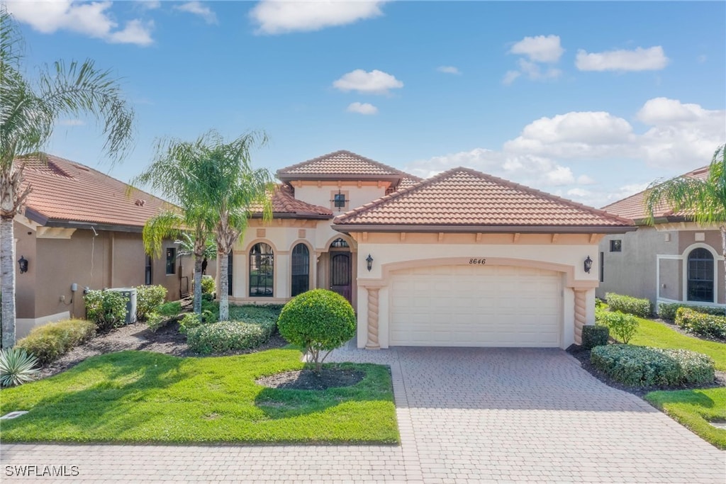 mediterranean / spanish home featuring a garage and a front lawn