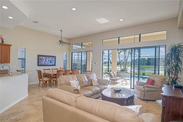 living room featuring light tile patterned floors, ceiling fan, and sink