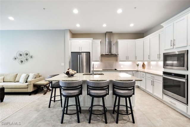 kitchen featuring white cabinetry, sink, wall chimney range hood, and stainless steel appliances