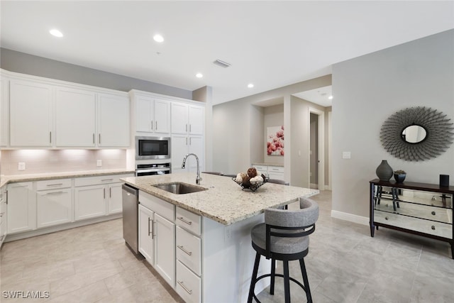 kitchen featuring stainless steel appliances, white cabinetry, a kitchen island with sink, and sink