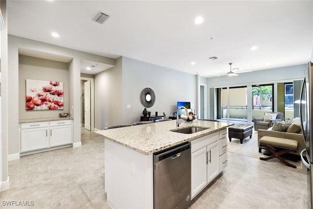 kitchen featuring a kitchen island with sink, sink, appliances with stainless steel finishes, light stone counters, and white cabinetry