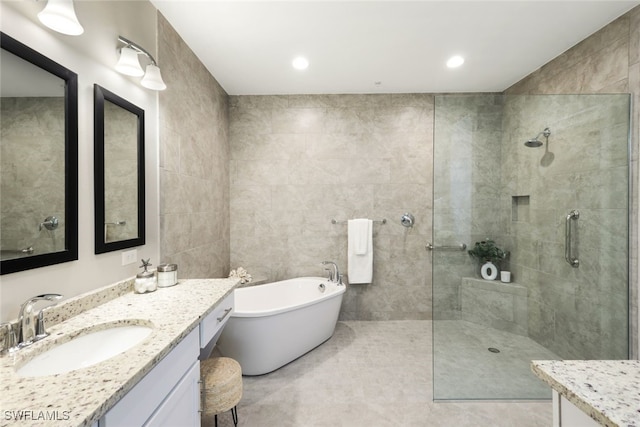 bathroom with tile patterned flooring, vanity, tile walls, and independent shower and bath