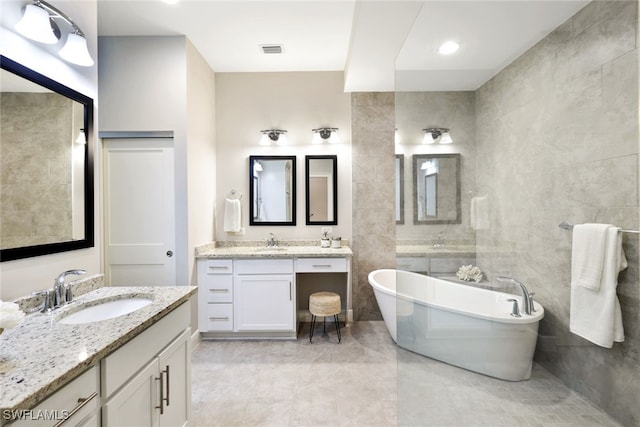 bathroom with tile patterned flooring, vanity, a tub, and tile walls