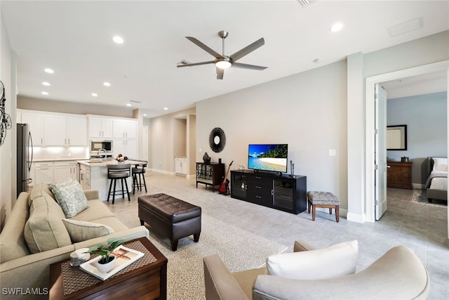 tiled living room with ceiling fan and sink