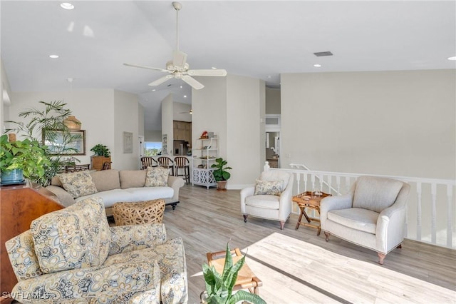 living room with ceiling fan, light hardwood / wood-style floors, and lofted ceiling