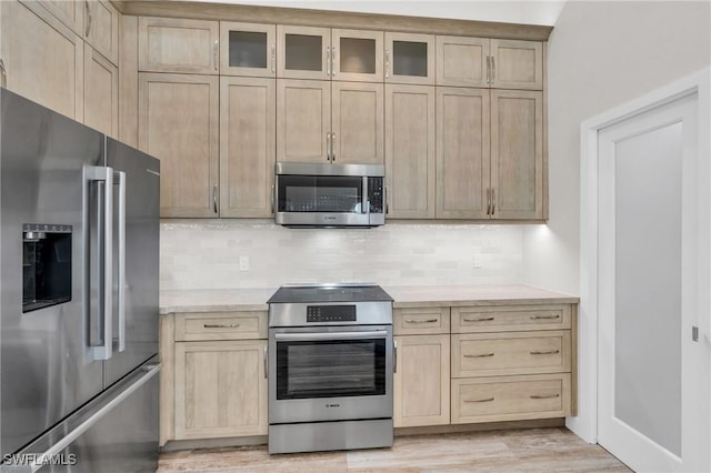 kitchen featuring tasteful backsplash, light brown cabinets, light hardwood / wood-style floors, and appliances with stainless steel finishes