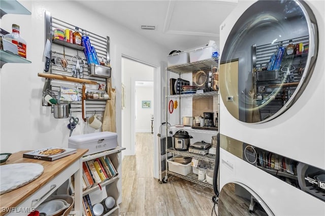 laundry room featuring stacked washer / drying machine and light wood-type flooring