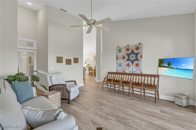 living room with ceiling fan, vaulted ceiling, and light wood-type flooring