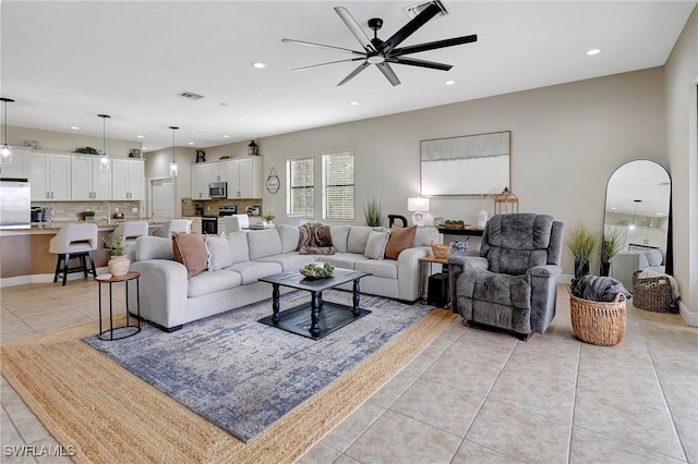 living room featuring ceiling fan, light tile patterned floors, and sink