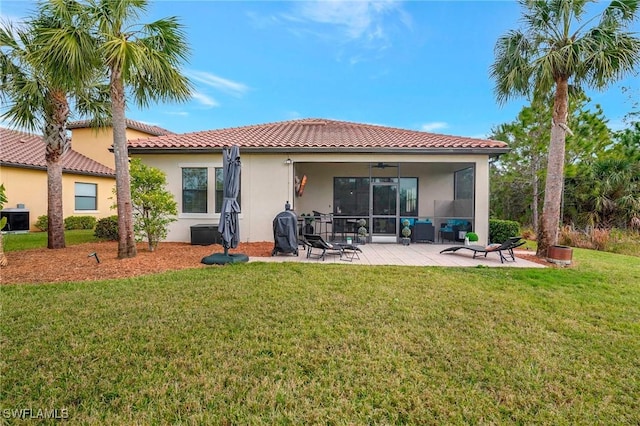 rear view of house featuring ceiling fan, a patio area, and a lawn