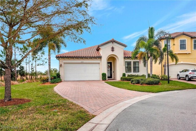 mediterranean / spanish house featuring a garage and a front yard