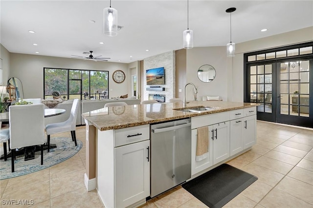 kitchen featuring white cabinets, decorative light fixtures, a kitchen island with sink, ceiling fan, and stainless steel dishwasher