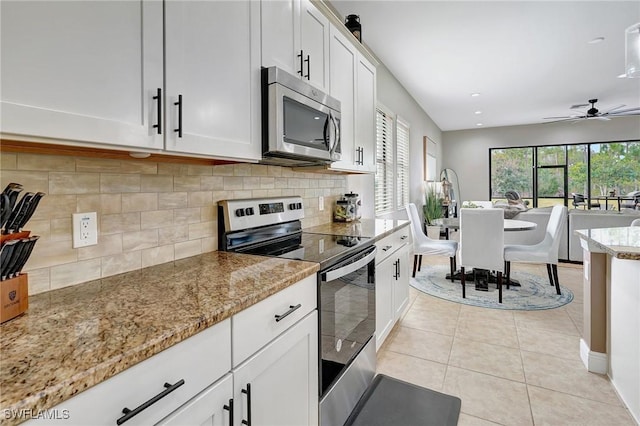 kitchen featuring light tile patterned floors, white cabinetry, ceiling fan, appliances with stainless steel finishes, and light stone countertops