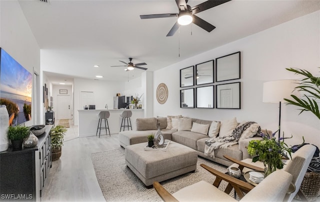 living room with ceiling fan and light hardwood / wood-style flooring