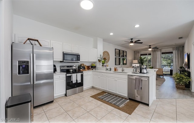 kitchen featuring light tile patterned floors, light countertops, appliances with stainless steel finishes, a sink, and a peninsula