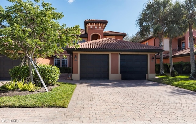 mediterranean / spanish-style house with a garage, decorative driveway, a tile roof, and stucco siding