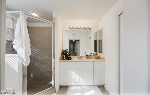 bathroom with a shower with door, vanity, and a textured ceiling