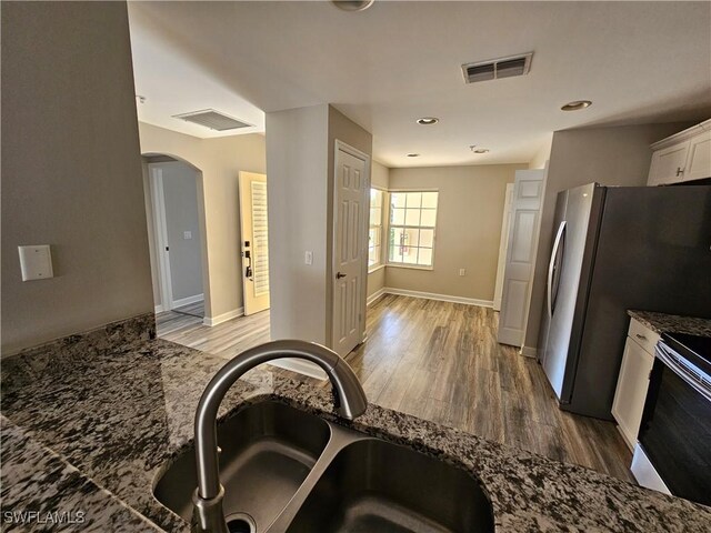 kitchen with white cabinetry, sink, stove, and dark stone countertops