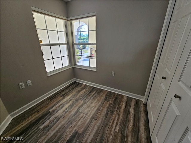 empty room with dark hardwood / wood-style floors and a wealth of natural light