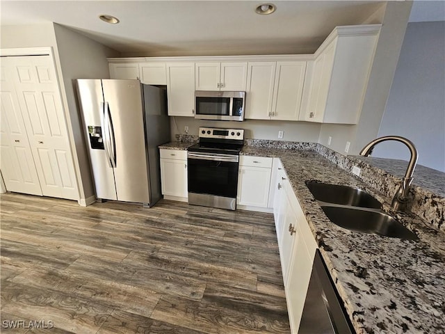 kitchen with white cabinetry, sink, dark hardwood / wood-style flooring, dark stone counters, and stainless steel appliances